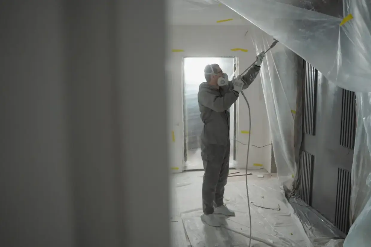 Texture applied with spray equipment and protective gear in an interior room